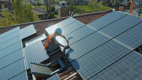 Technician with hard hat installing solar panel installed on home rooftop Stock Footage 127668782