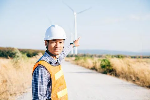 Technician helmet-clad engineer inspects windmill farm Stock Photos