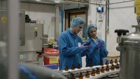 Technician helping production workers in inspecting bottles in factory Video stock 107954388