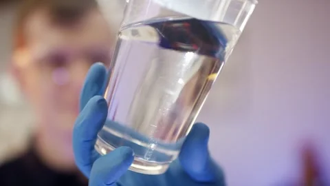 Technician Holding Glass Beaker with Clear Liquid, Bright Laboratory, Close Up Stock Footage 341297972