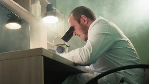 Technician Inspecting Circuit Board Under Microscope in Detailed Workspace Stock Footage 282301437