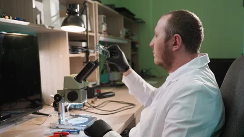 Technician Inspecting Circuit Board Under Microscope in Organized Electronics Video stock 284359360