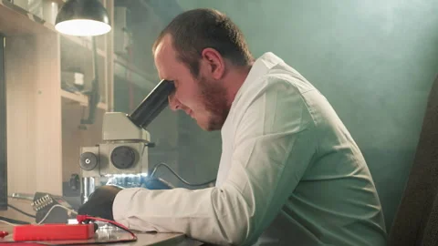Technician Inspecting Circuit Board Under Microscope in Detailed Electronic Stock Footage 284359664