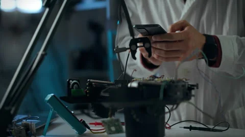 Technician inspecting electronic components while utilizing a smartphone in Stock Footage 289572792