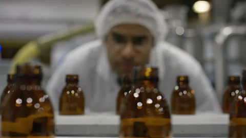 Technician inspecting empty bottles on production line in cosmetic factory Stock Footage 107985449