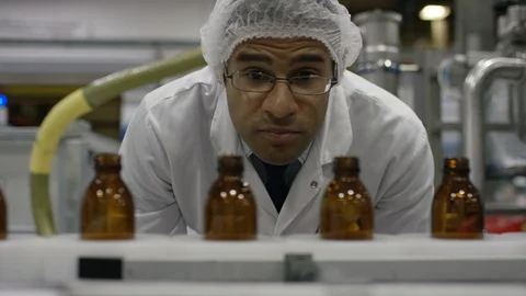 Technician inspecting empty bottles on production line in cosmetic factory Stock Footage 107986071