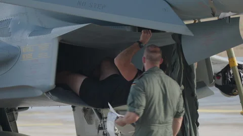 Technician inspecting military jet underside Видео 330144040