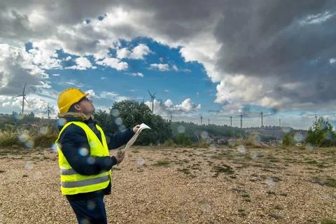 Technician inspecting wind turbines in a cloudy day for renewable energy pr.. Stock Photos