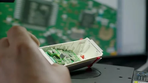 Technician Inspects Circuit Board by Hand with PCB Design Shown on Computer Moni Stock Footage 334053603