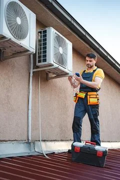 Technician installing and checking air conditioning unit on the roof Stock Photos