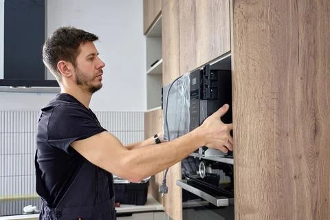 Technician installing built in microwave oven in kitchen cabinet Stock Photos