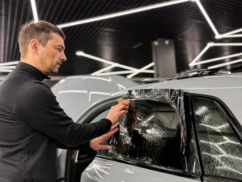 Technician Installing car window tint. Window toned film. Car window tintin.. Stock Photos