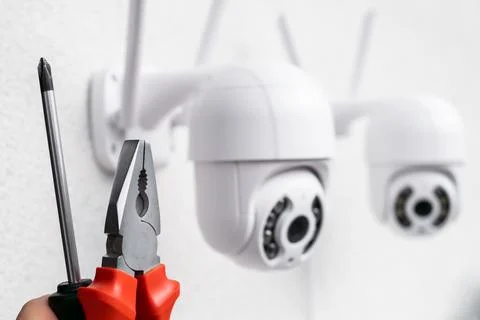 Technician installing CCTV camera using pliers and screwdriver Stock Photos