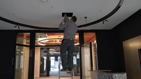 Technician installing a drywall ceiling access panel in a modern office Stock Footage 334266826