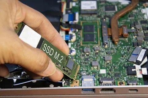 The technician is installing an M.2 hard drive. Stock Photos