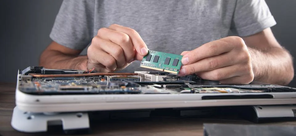 Technician installing random access memory on laptop computer. Stock Photos