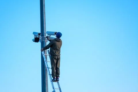 Technician installing security cameras on pole Stock Photos