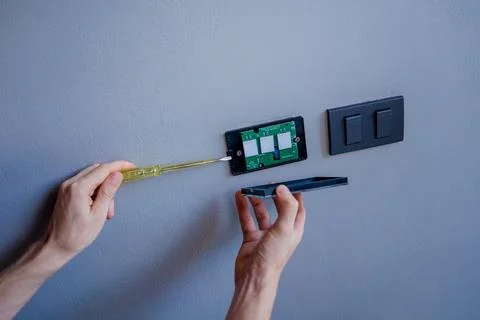 Technician installing sensor light switch at modern villa Stock Photos