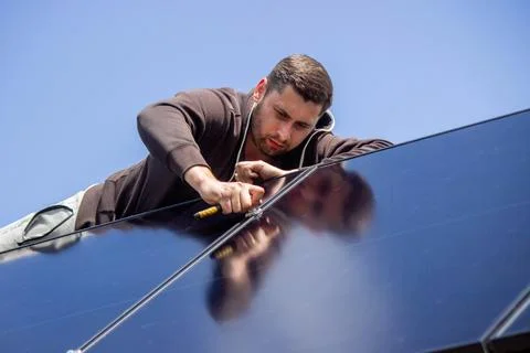 Technician installing solar panel mount on a residential house roof close up Stock Photos