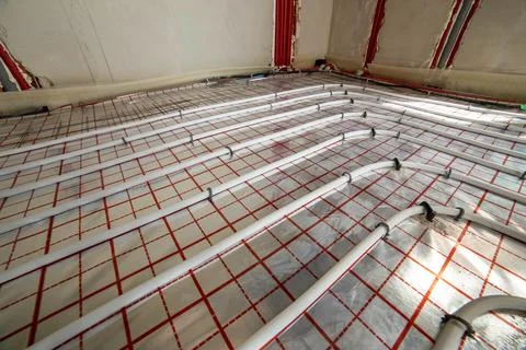 Technician installing underfloor heating pipes on insulated flooring, demon.. Stock Photos