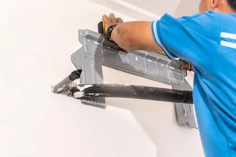 Technician installing wall bracket of air conditioning condenser unit Stock Photos