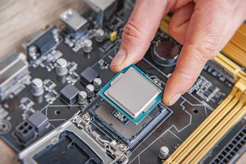 A technician installs a central processing unit into a motherboard socket during Stock Photos