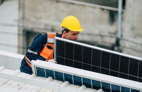 Technician installs solar panel on rooftop in urban location during dayligh.. Stock Photos