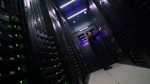 Technician IT engineers stands between rows server racks while check diagnostic Stock Footage 347901523