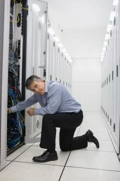 Technician kneeling and repairing a server Stock Photos
