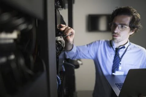 Technician with laptop working at server panel in server room Foto stock