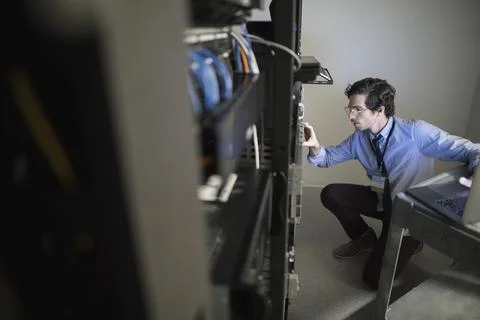 Technician with laptop working at server panel in server room Foto stock