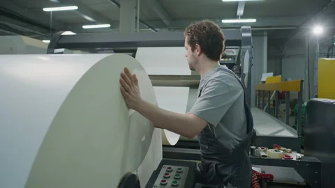 Technician Loading Massive Paper Roll onto Web Press in Printing Factory Stock Footage 335483612