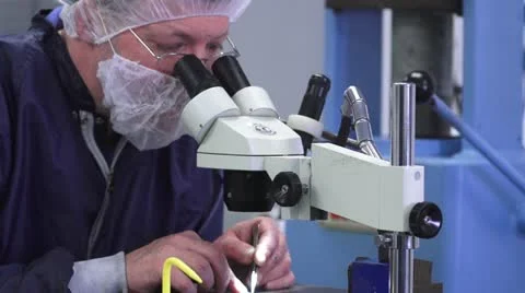 Technician Looking in Microscope in Cleanroom Stock Footage