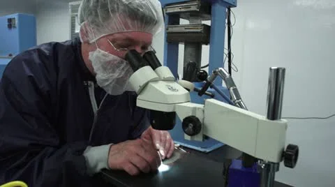 Technician Looking through Microscope in Cleanroom Stock Footage 10895761
