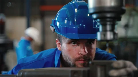 Technician looks down at a workpiece inside a metal lathe shop. Stock Footage 257158355