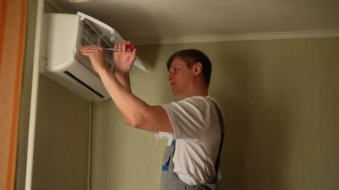 Technician male in uniform using screwdriver while repairing or installing air Stock Footage 294833408