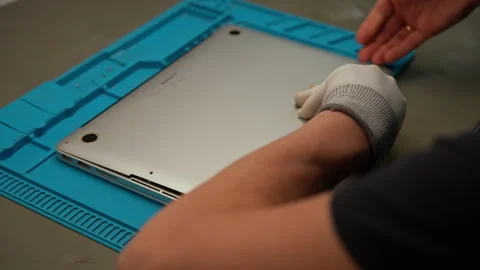 Technician male wearing gloves disassembling laptop on workbench, engaging in Stock Footage 306891678