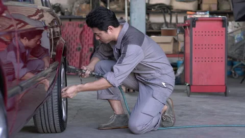 Technician man checking pressure and inflating car tire in garage. 스톡 동영상 173649946