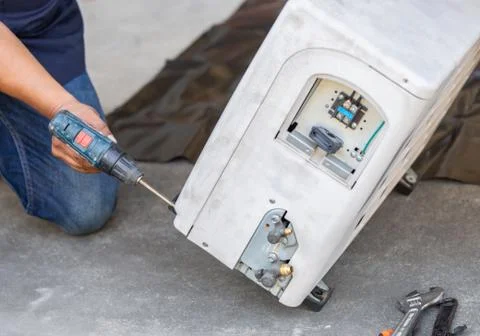 Technician man hands using a screwdriver fixing modern air conditioning system 写真素材