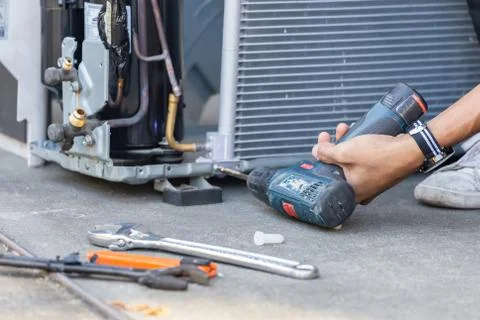 Technician man hands using a screwdriver fixing modern air conditioning system Фото