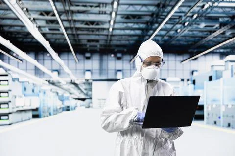 Technician man inspecting semiconductor production infrastructure with laptop Stock Photos