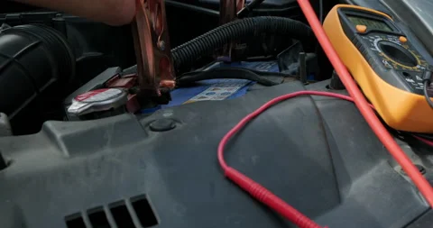 Technician man uses multimeter voltmeter to check voltage level in car battery Stock Footage 146109107