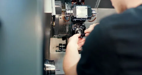 Technician manually adjusting high precision CNC machine tool in factory Stockbeeldmateriaal 329681191