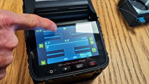 Technician manually adjusting an optical fiber fusion splicer on a wooden table Stock Footage 342770864
