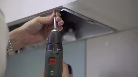 Technician master fastens the hood to the kitchen module with a screwdriver. Stock Footage 157288442