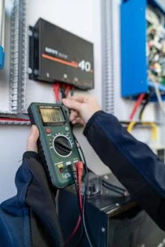 Technician measuring solar charge controller voltage with multimeter Stock Photos