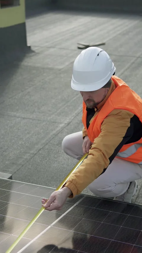 Technician measuring a solar panel on a rooftop during installation. Video stock 321053947