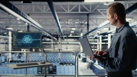Technician monitors server room activity using laptop while walking in facility Stock Footage 314683361