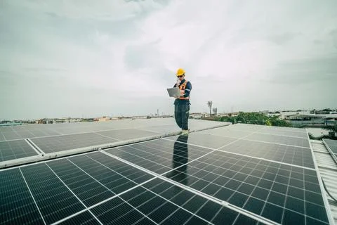Technician monitors solar panel performance on rooftop in urban setting dur.. Stock Photos