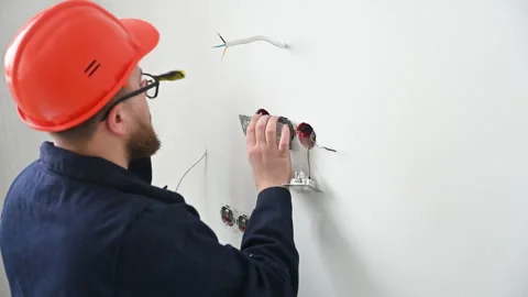Technician mounts power outlet on indoor wall. Close view of electrician fixing Stock Footage 346767723